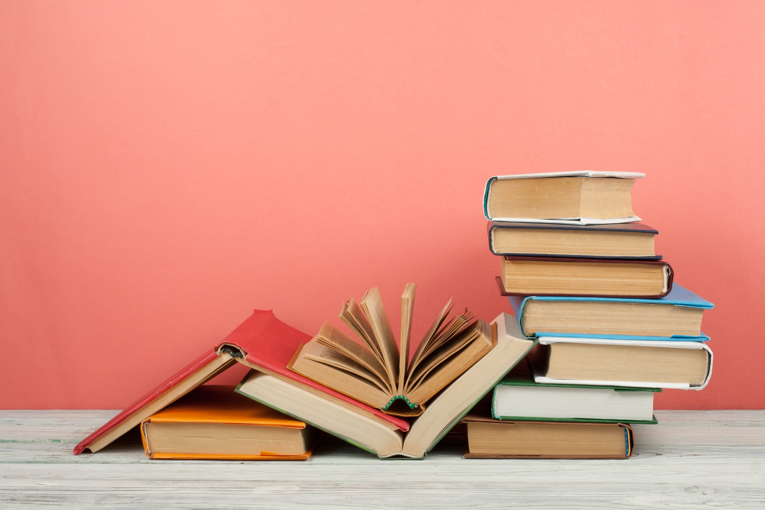 Apilamiento de libros. Libro abierto, libros de tapa dura sobre mesa de madera y fondo rosa. De vuelta a la escuela. Copiar espacio para texto